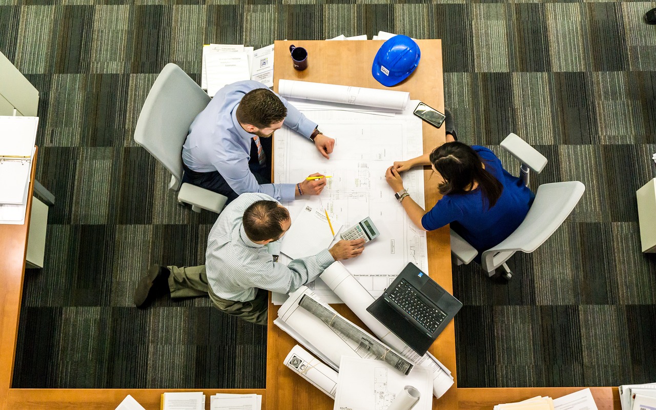 image of office workers sitting at the table from above heading an article about Employee Share Schemes by EM Law