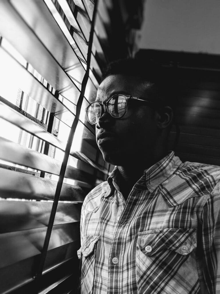 image of a man looking outside through open blinds inside the article by EM Law about NDA