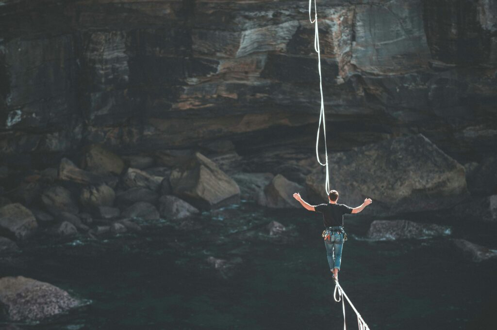 image of a man walking on rope in between two cliffs heading an article by EM Law about Novation