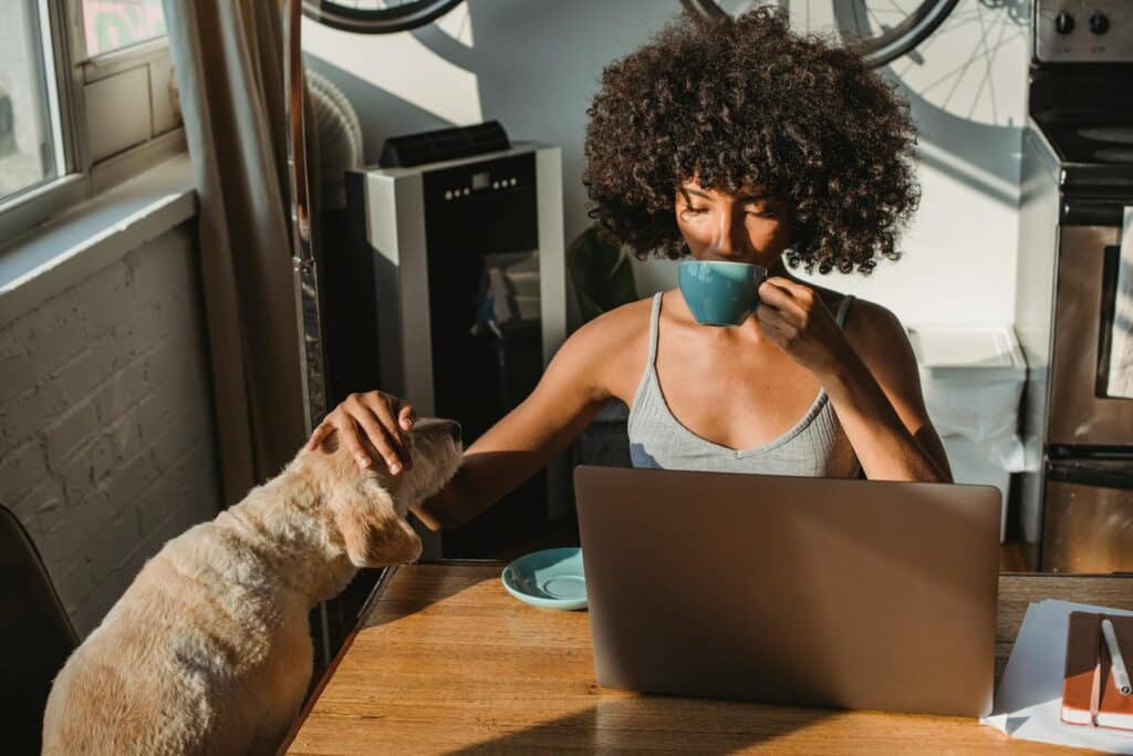 image of a woman drinking coffee and petting her dog while working inside an article by EM Law about Employment rights bill