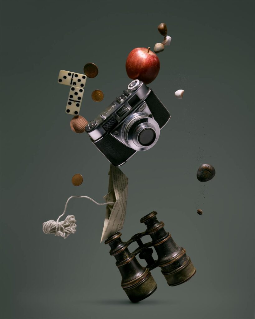 image of falling binoculars, apple, domino piece and a camera