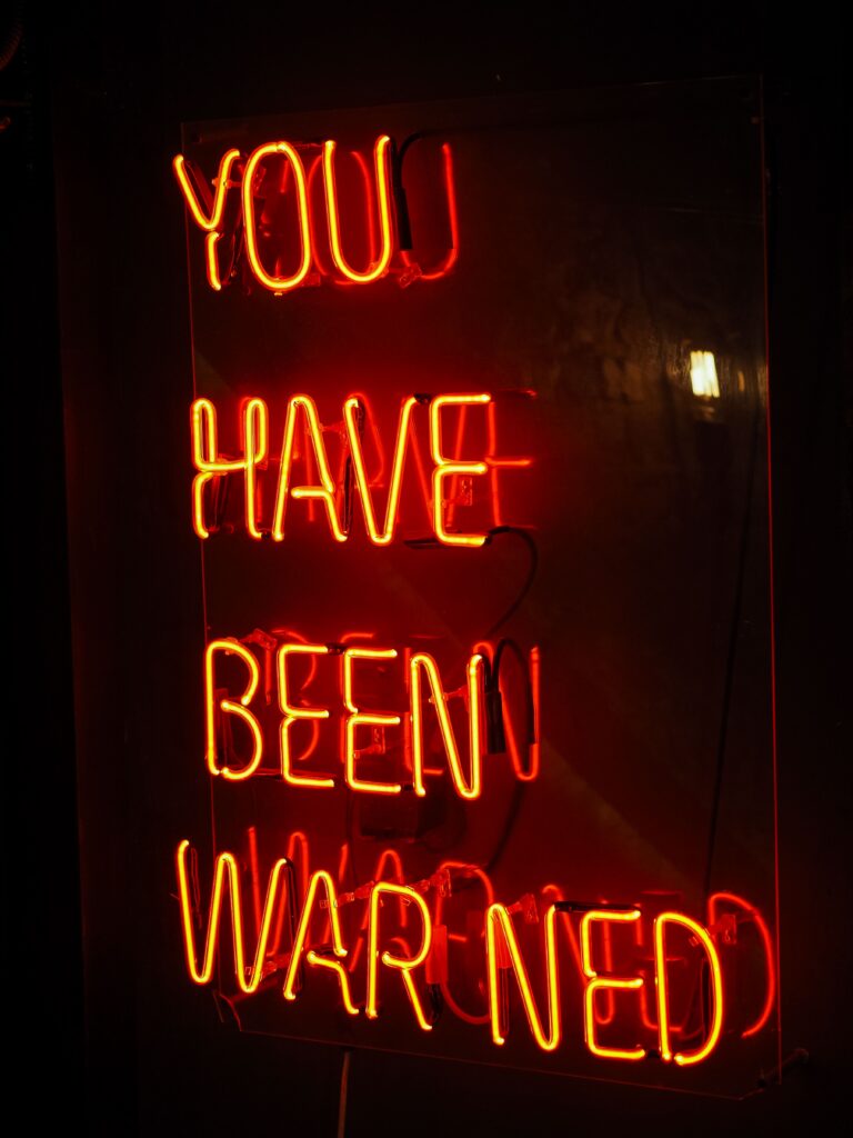 Neon Warning sign in an EM Law blog about Disclaimers in SaaS contracts